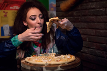 young woman with appetite eating pizza in cafe