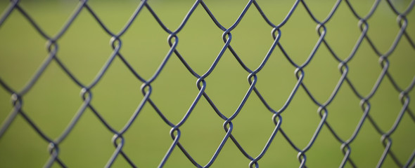 Naklejka premium Steel wire mesh fence with green blurred background. Close up view with details.