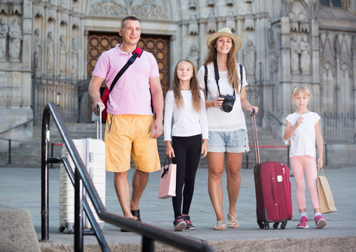 Joyful family of tourists walking with suitcases