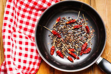 Black pepper peas and dried chili peppers on a frying pan 