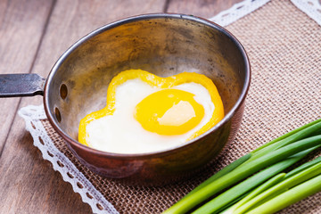 Bell pepper egg rings on a cooking pan and green onion 