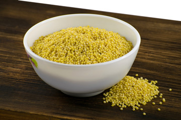 Millet in white bowl on brown board. Wheat. Healthy dietary groats background.