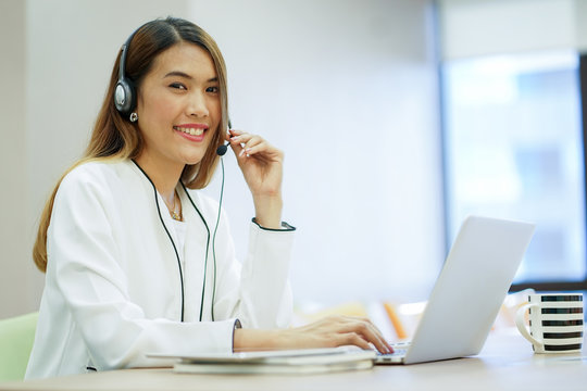 close up focus on asian call centre woman with headphone trying to response answer or working in operation office room.helpdesk hotline concept.