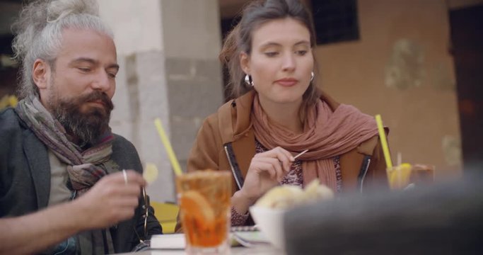 Woman and man talking having cocktail aperitif outside of cafe.Close shot. Caucasian couple in love roadtrip vacation italian travel 