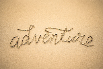 Adventure word is written on the beach sand