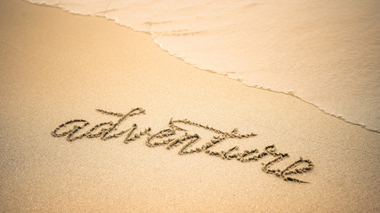 Adventure word is written on the beach sand
