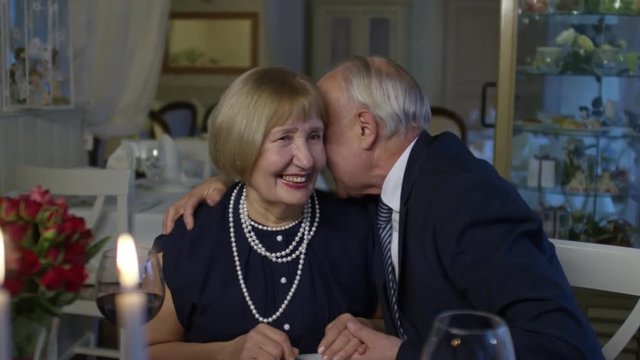 PAN of loving elderly couple flirting and hugging during romantic date in restaurant
