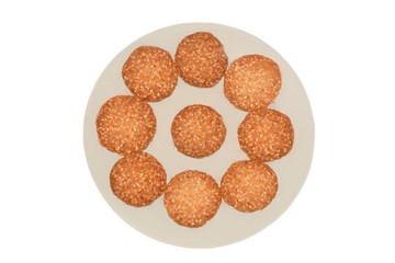 Cookies with sesame seeds on a beige plate isolated on white background. The view from the top