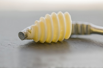 A butter curly with its butter curler. Close up.