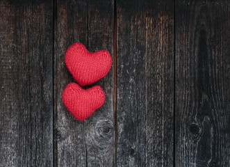 Fototapeta premium two bright red hearts made of yarn on a background of the wooden walls of old dark tar boards