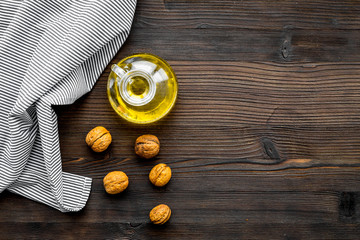 Oil as cosmetics. Walnut oil near walnut in nutshell on dark wooden background top view copy space