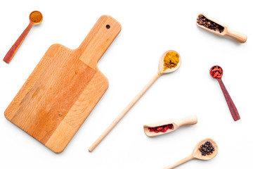 Mock up for menu or recipe. Wooden cutting board near scoops and spoons with spices on white background top view