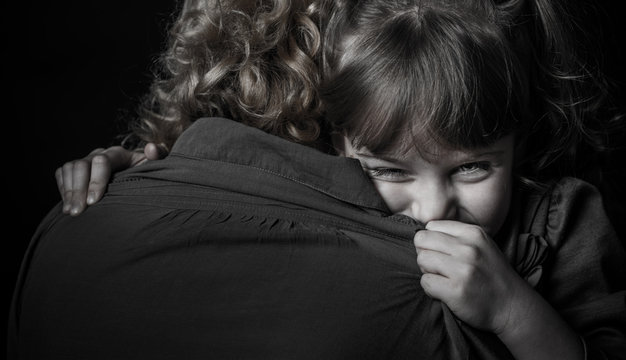 Photo shooting indoors. On a black background. Child ( girl ) hugs his mother.
