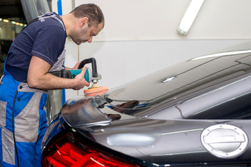 A man polishes a black car with a polisher