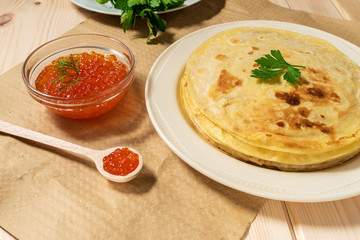 Pancakes with red caviar on plate. Russian cuisine. Maslenitsa.