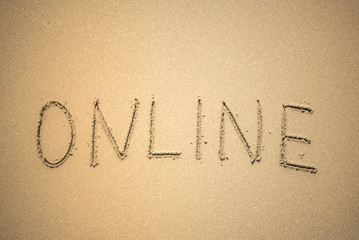 Online word is written on the beach sand