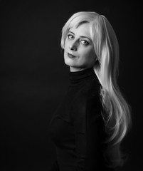 Photo shooting indoors. On a black background. A woman with long white hair, wearing a black...