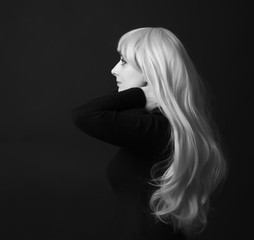 Photo shooting indoors. On a black background. A woman with long white hair, wearing a black jacket.
