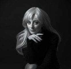 Photo shooting indoors. On a black background. A woman with long white hair, wearing a black...