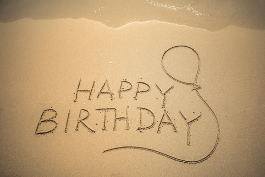 Happy Birthday word is written on the beach sand