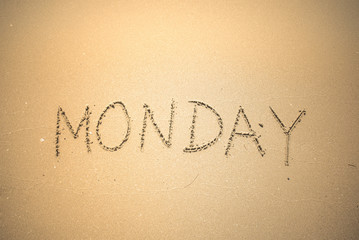 Monday word is written on the beach sand