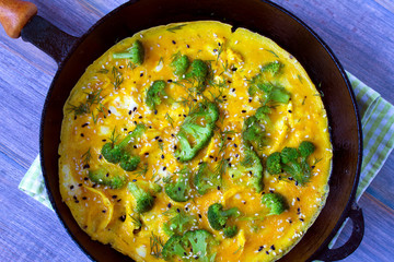 Omelette with broccoli, herbs and sesame seeds in frying pan