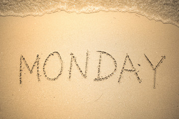 Monday word is written on the beach sand