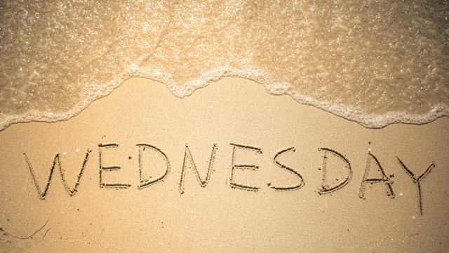 Wednesday word is written on the beach sand