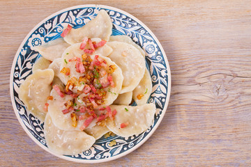 Dumplings with filling: cabbage and carrot, served with bacon and onion. Varenyky, vareniki, pierogi, pyrohy. Horizontal, overhead