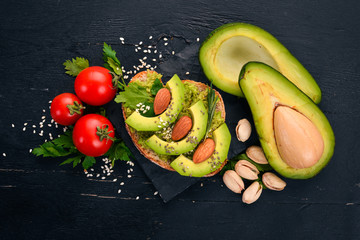 Sandwich with avocados and almonds. On a wooden background. Top view. Free space for your text.