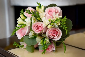 A wedding bouquet of pink roses and white flowers on the table at home.