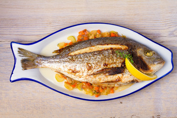 Whole dorado or dorada fish with vegetables, thyme and lemon. View from above, top, horizontal