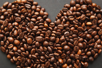 Brown coffee beans in form of heart isolated on black texture background for design, part or half. Saint Valentine's Day card on fabruary 14, holiday concept.