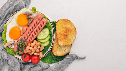 English breakfast tomatoes, sausages, beans, mushrooms, eggs,toast and herbs top view. On a white wooden background.