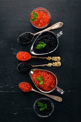 Spoon with black and red caviar on a wooden background. Top view. Free space for text.