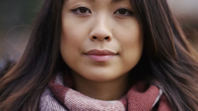 Portrait of attractive chinese female smiling to camera, in slow motion
