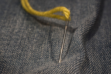 close up, yellow needle and thread on jeans cloth