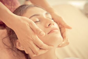 Therapist hand is massaging on a woman face in spa
