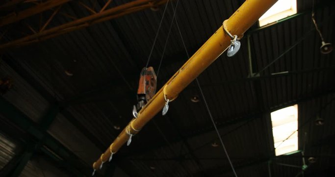 Close up of a big crane transporting a big long steel detail of construction. Indoors