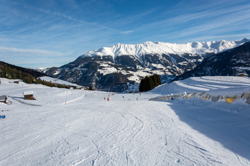 Fototapeta na wymiar Slope and yellow gondolas in ski resort Serfaus Fiss Ladis in Austria with snowy mountains