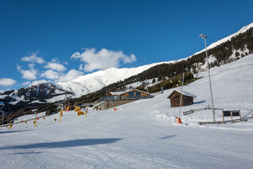 Fototapeta na wymiar Slope and yellow gondolas with chalet in ski resort Serfaus Fiss Ladis in Austria with snowy mountains