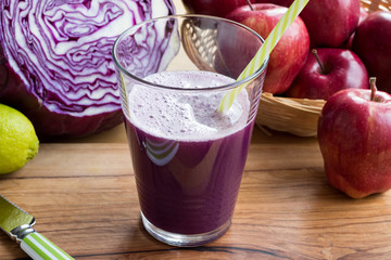 Purple cabbage juice in a glass, with cabbage in the background