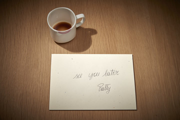 una tazzina bianca lasciata come gesto  di presenza quotidiana sul tavolo con fondo di caffè e...