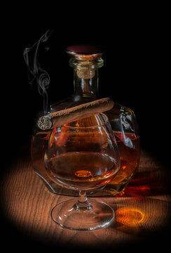 A glass of cognac with a cigarette and a bottle of cognac