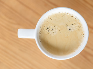 Kaffee in einer weißen Tasse auf einem Holztisch - Flat Lay