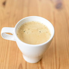 Kaffe in einer weißen Tasse auf einem Holztisch