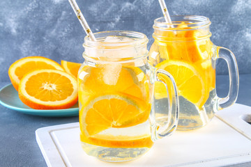 Orange detox water in mason jars on a gray concrete background. Healthy food, drinks.