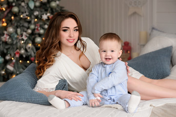 Merry Christmas celebration. Beautiful mom and little son at home near the Christmas tree. Christmas miracles. Happy New Year