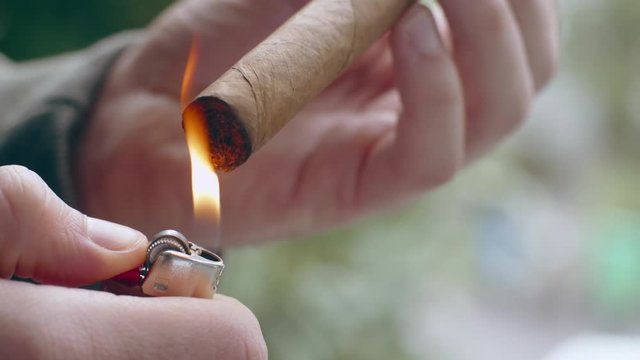 Close-up of hispanic man lighting end of fine cigar