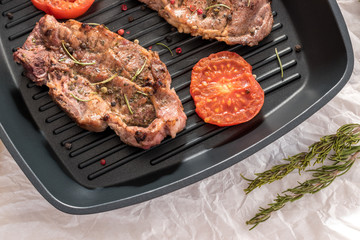 Grilled steak on grill pan with tomatoes and lemon on white background